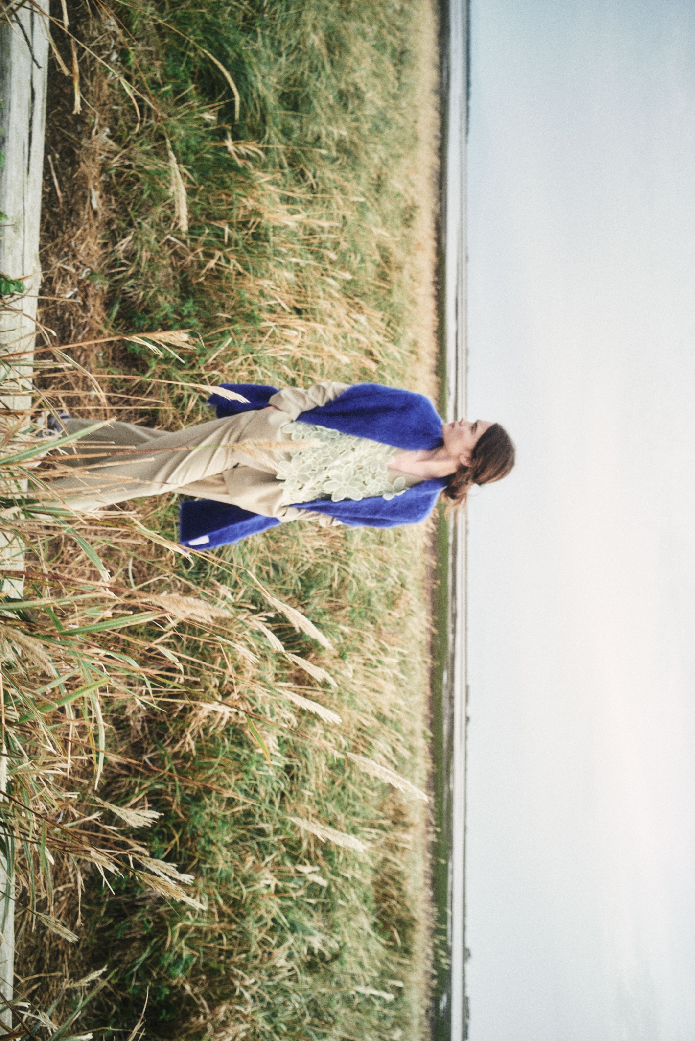 ダブルブレストテーラードジャケット・フラワーオーガンジービスチェ・ワイドレッグタック入りパンツ・シャギーマフラーを着用した女性