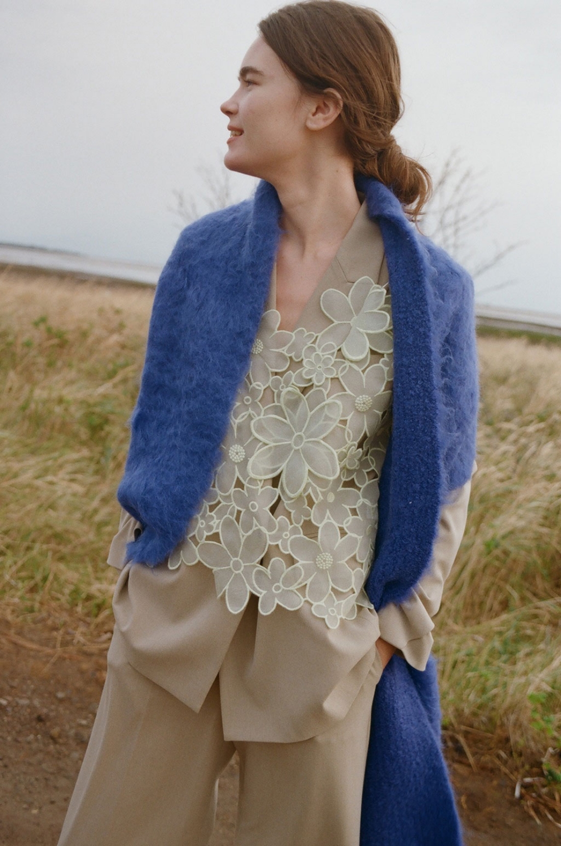 ダブルブレストテーラードジャケット・フラワーオーガンジービスチェ・ワイドレッグタック入りパンツ・シャギーマフラーを着用した女性