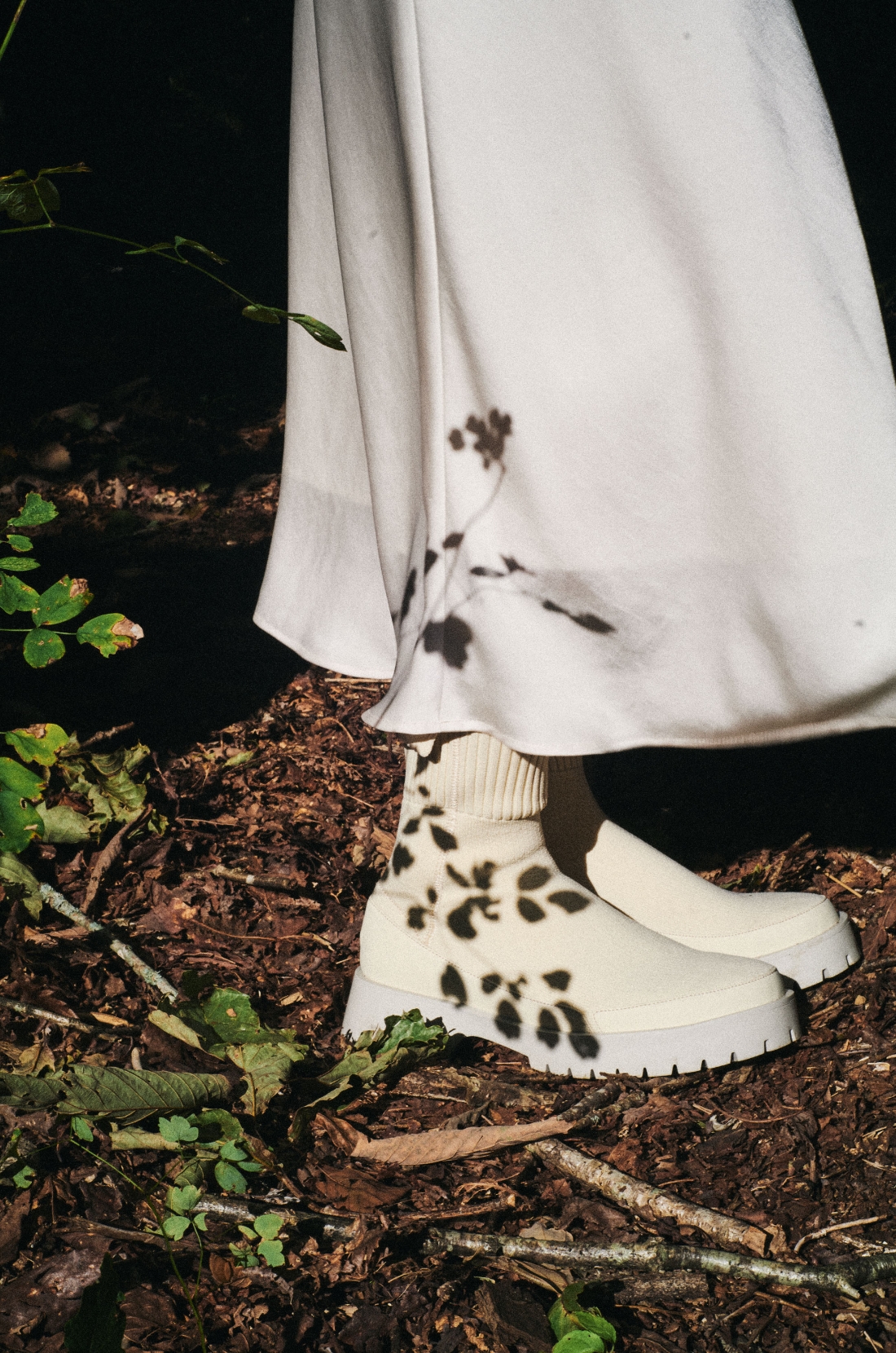 ボリュームボアコート・ギャザーフーディーブルゾン・ゴムウエストナロースカート・eco ナイロンスクエアバッグ・ecoニットブーツを着用した女性の足元