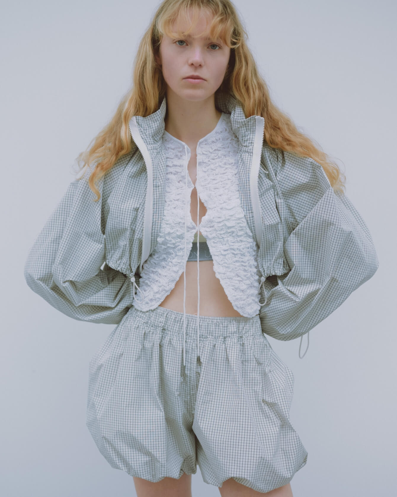 ドロストナイロンブルゾン、2wayシャーリングブラウス、リラックスヘルシーブラ、バルーンショートパンツを着用した女性モデル