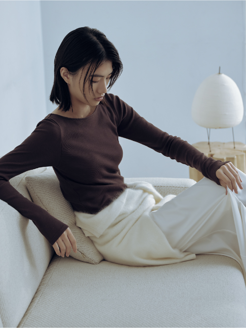 ロングスリーブトップスと白いスカートでくつろぐモデル
